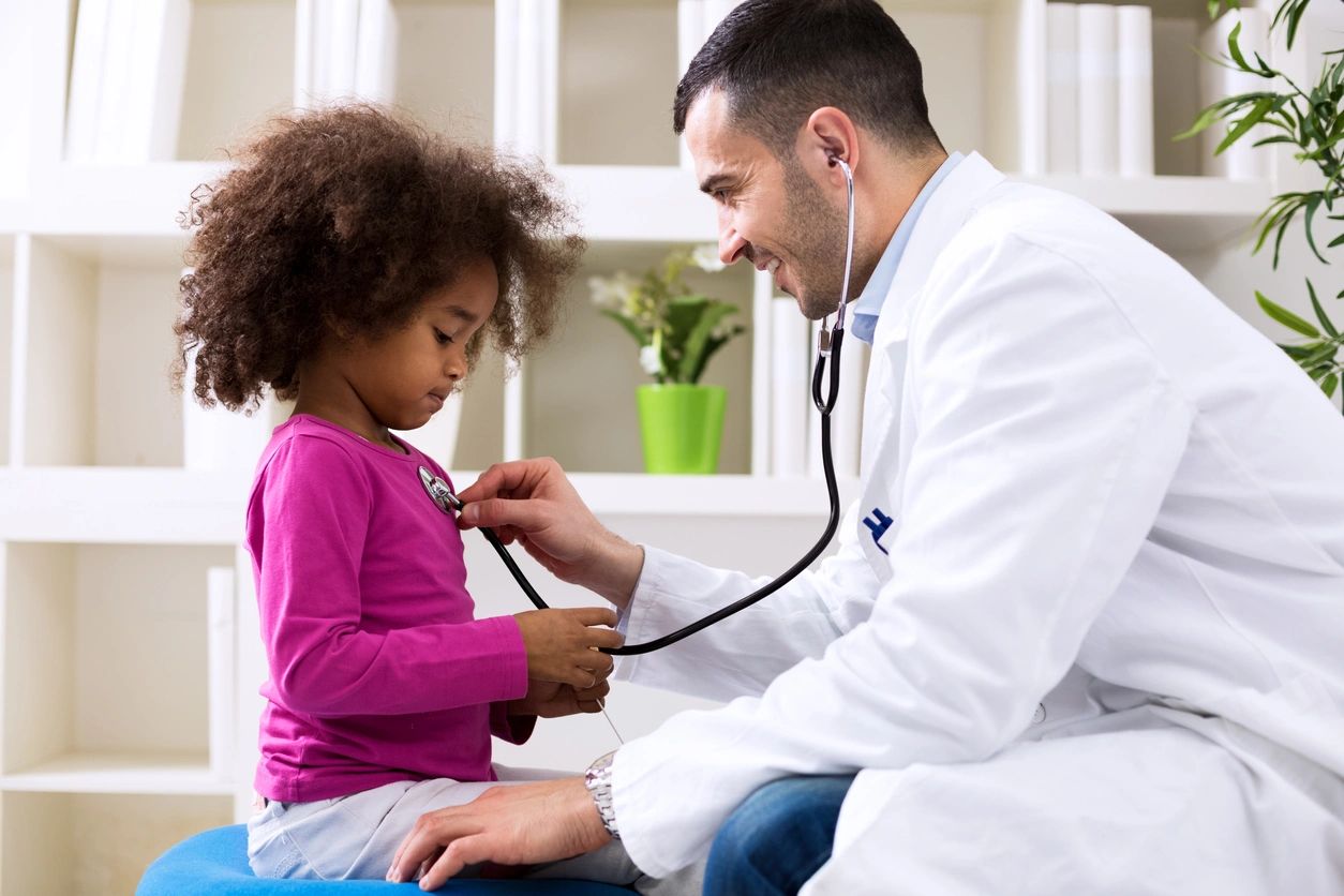 Male doctor checking the heartbeat of young girl